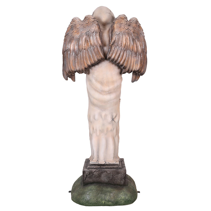 A faceless angel  statue holding a human head facing back